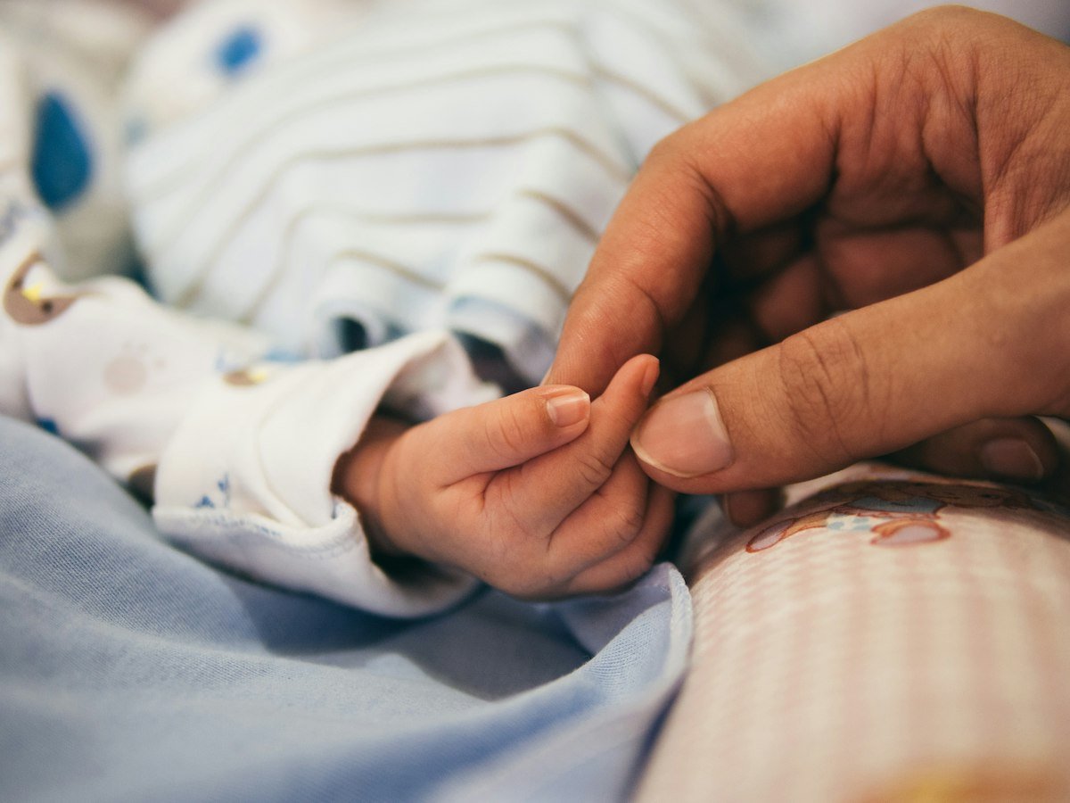 A parent holding their newborn's hand after birth